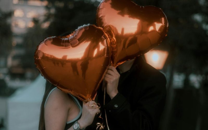 Casal segurando dois balões em formato de coração